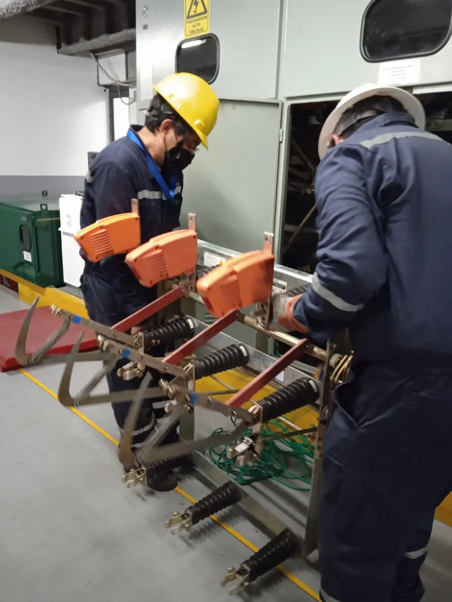 Técnicos probando un seccionador con equipo de medición color naranja